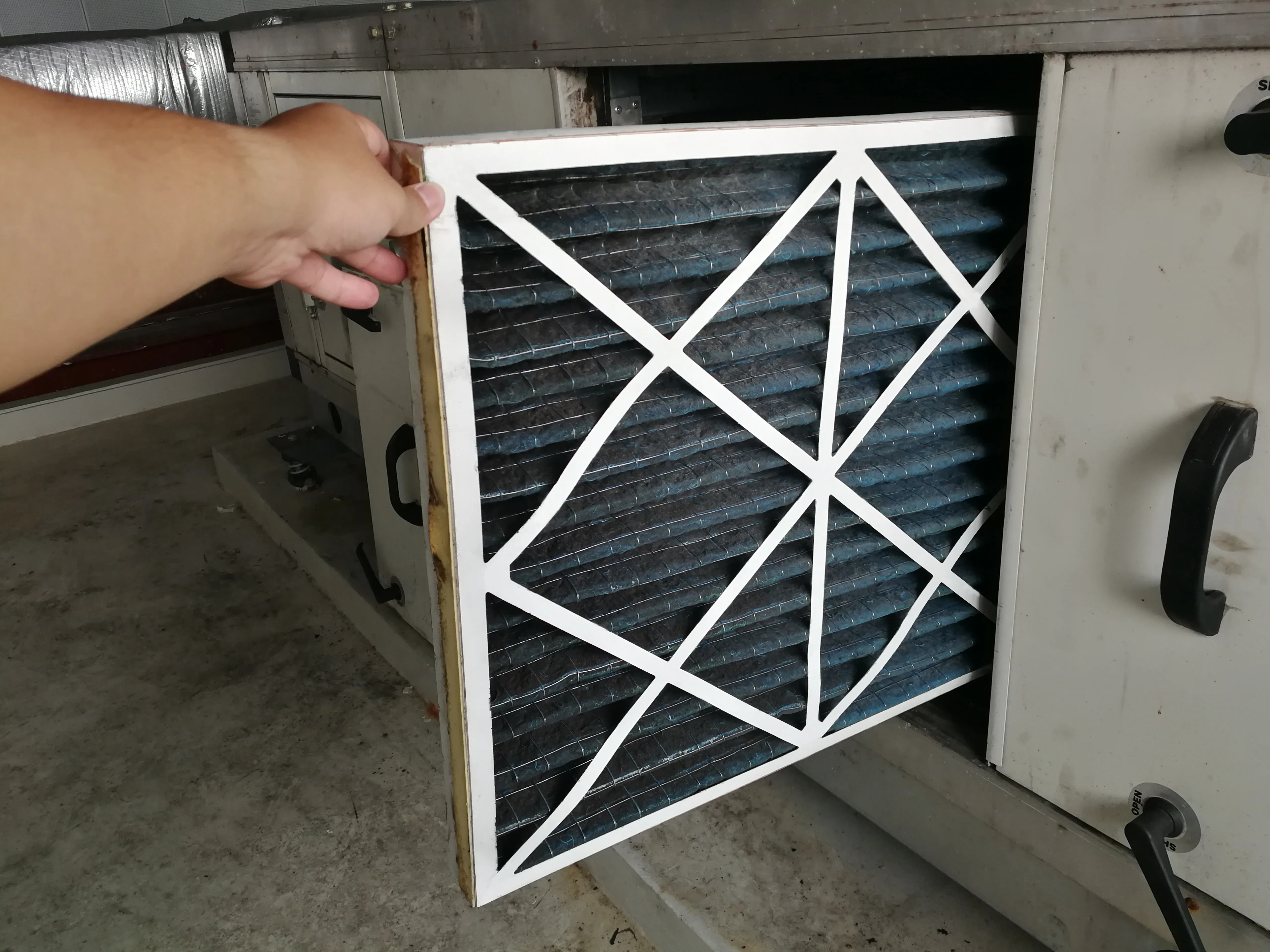 Un técnico que revisa un prefiltro de la unidad de manejo de aire para reemplazar un filtro nuevo: mantenimiento de HVAC.