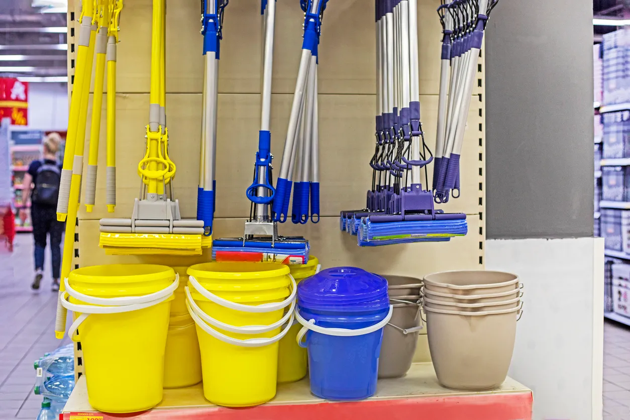 Mops amarillas y azules para fregar pisos con cubetas en el mostrador de la tienda. empresa de productos de limpieza