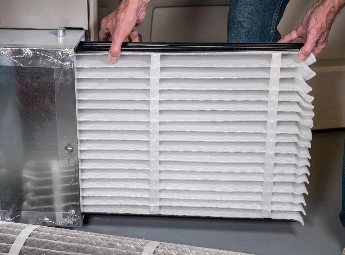 Hombre cambia un filtro de aire plegado en el sistema de calefacción, ventilación y aire acondicionado (HVAC)
