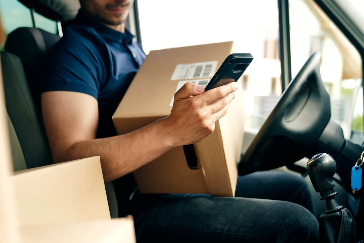 Primer plano de la comprobación de un paquete mediante un dispositivo de información portátil, un smartphone necesario. 