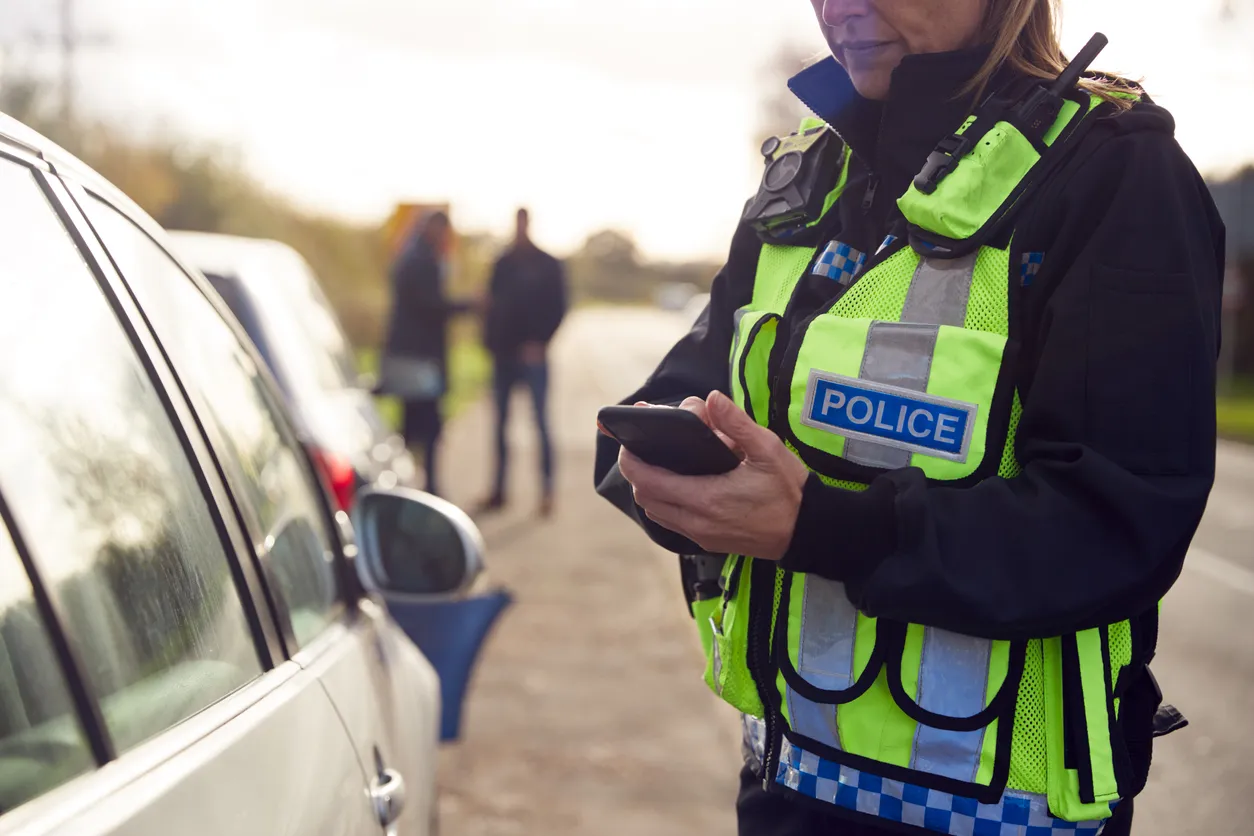 Una agente de policía de tráfico graba detalles de un accidente de tráfico en su teléfono móvil