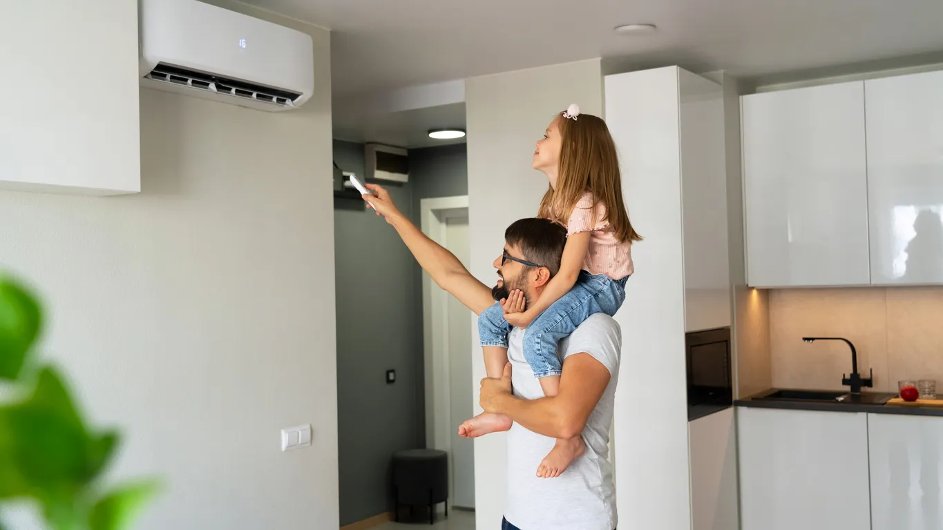 Padre e hija moviendo el control del aire acondicionado en el área de la cocina.