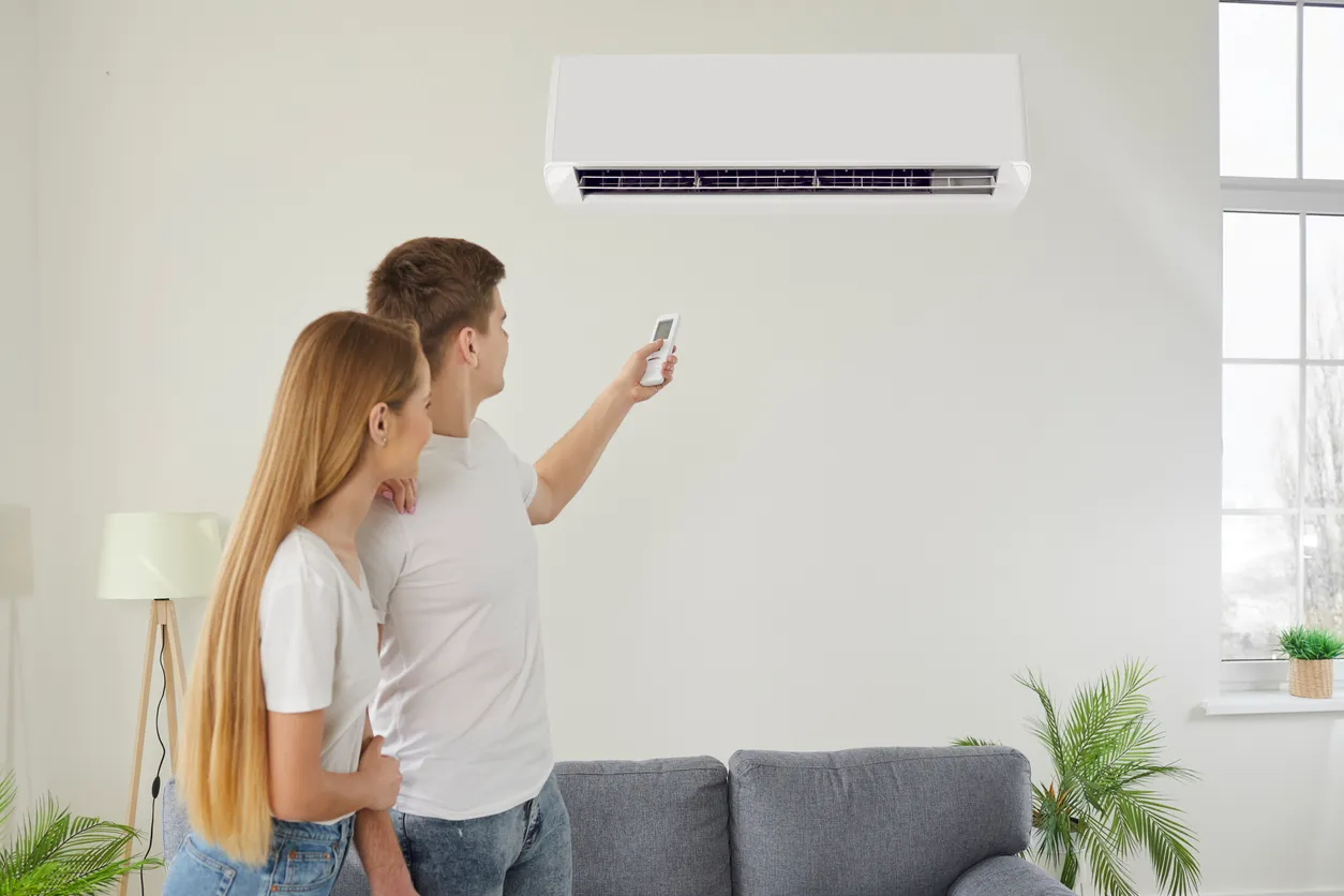 Una pareja activa y enciende el aire acondicionado de pared. Con precisión y facilidad, encienden el climatizador.