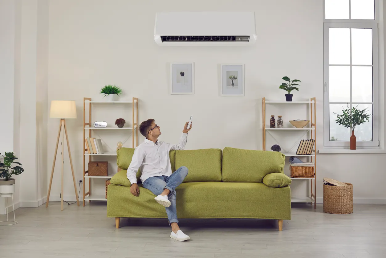 Un hombre cambia los modos del aire acondicionado para establecer una temperatura agradable mientras disfruta del aire fresco