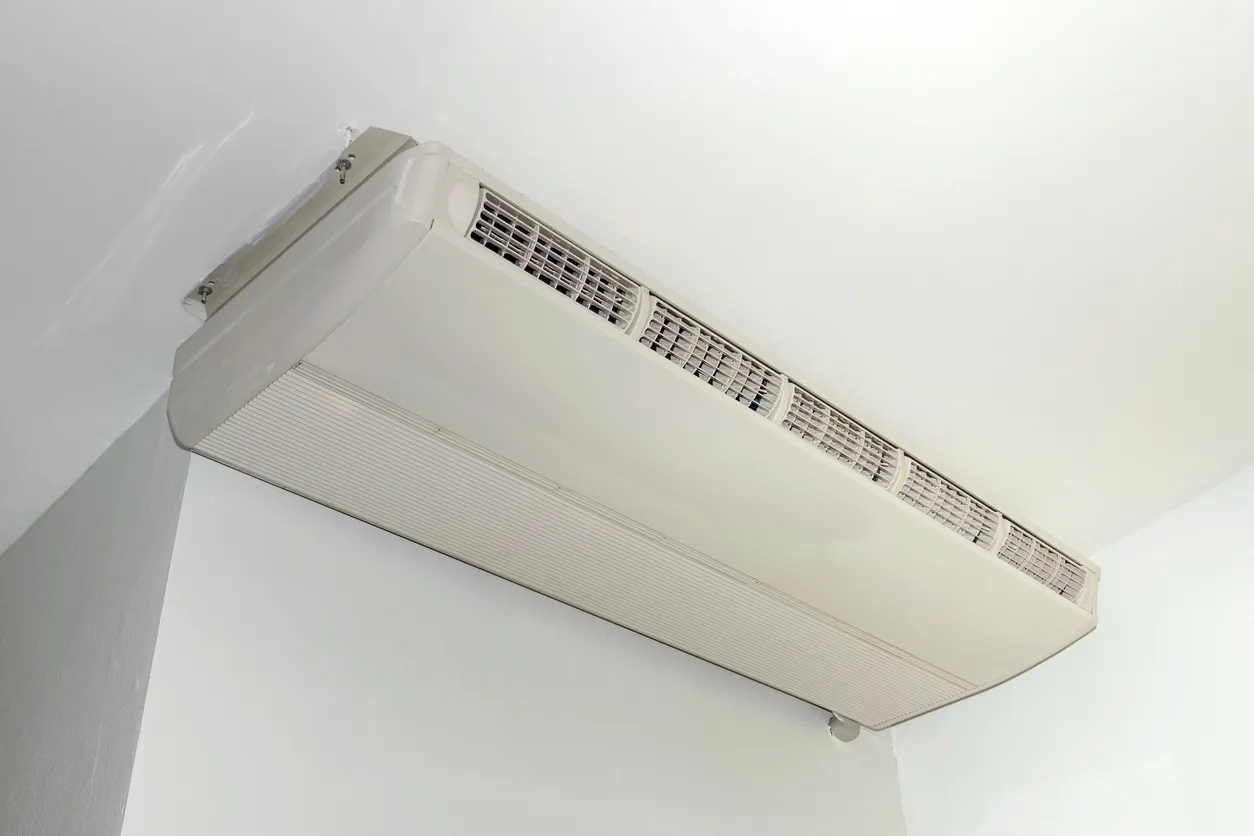 Aire acondicionado colgado en el techo de la habitación blanca.
