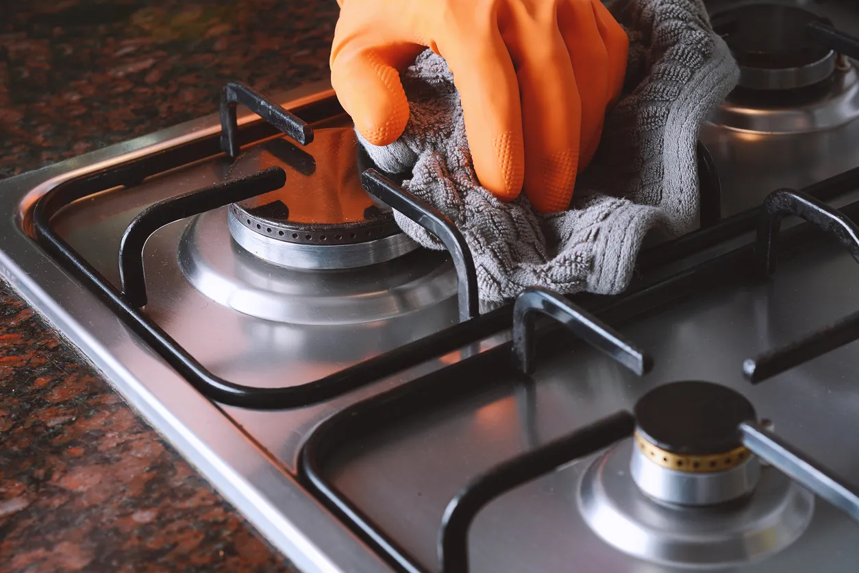 Vista de cerca de manos con guantes de goma limpiando la placa de cocina