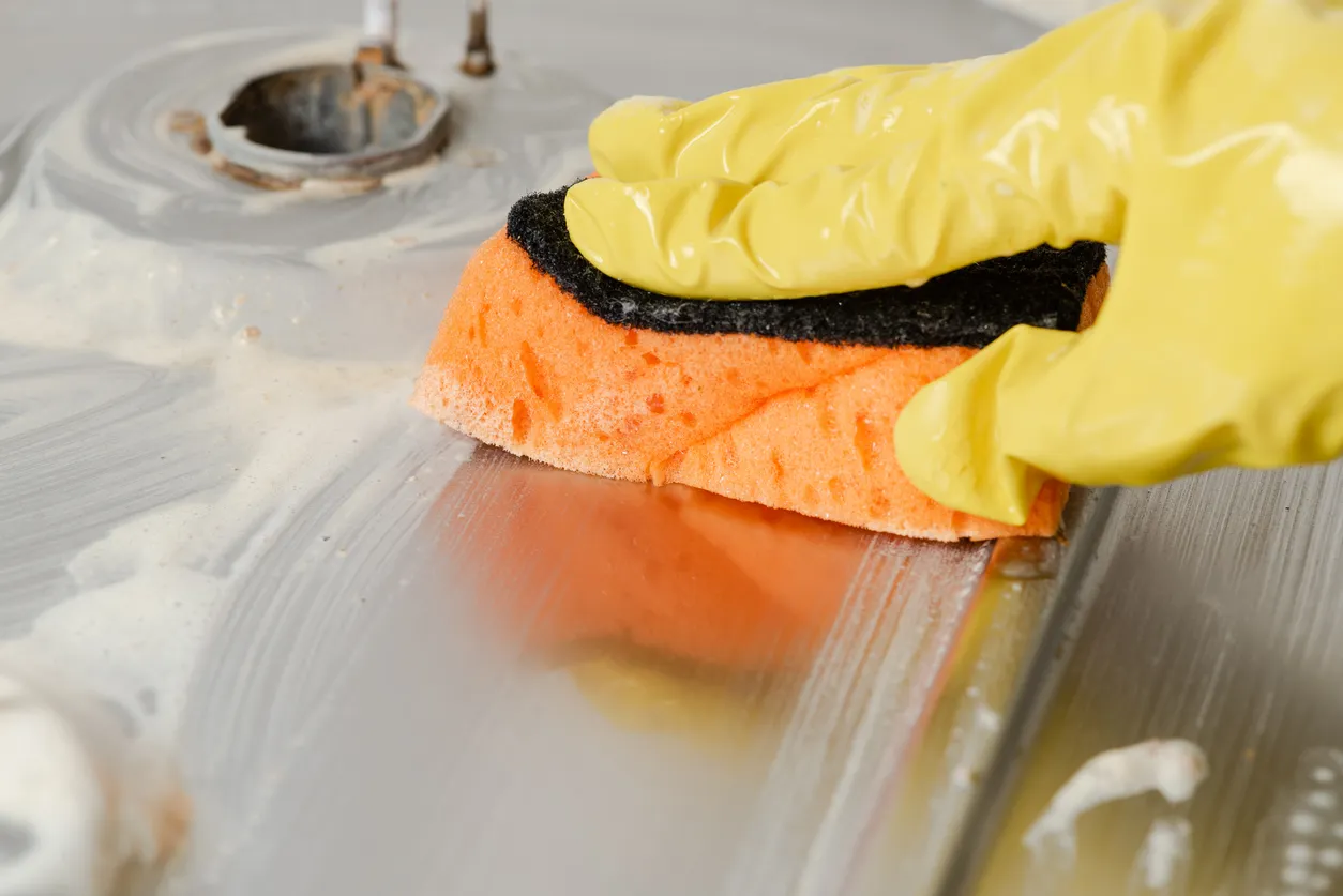 Primer plano de una mano limpiando una cocina de gas en la cocina