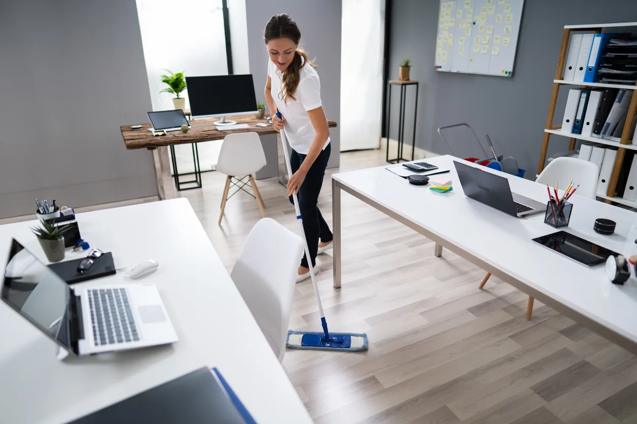 Mujer joven trapeando el piso en la oficina, como parte de los servicios de una empresa de limpieza especializada en oficinas