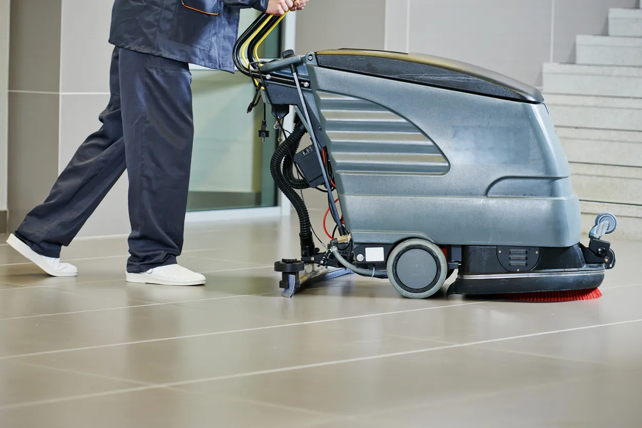 Trabajador limpiando el piso con máquina