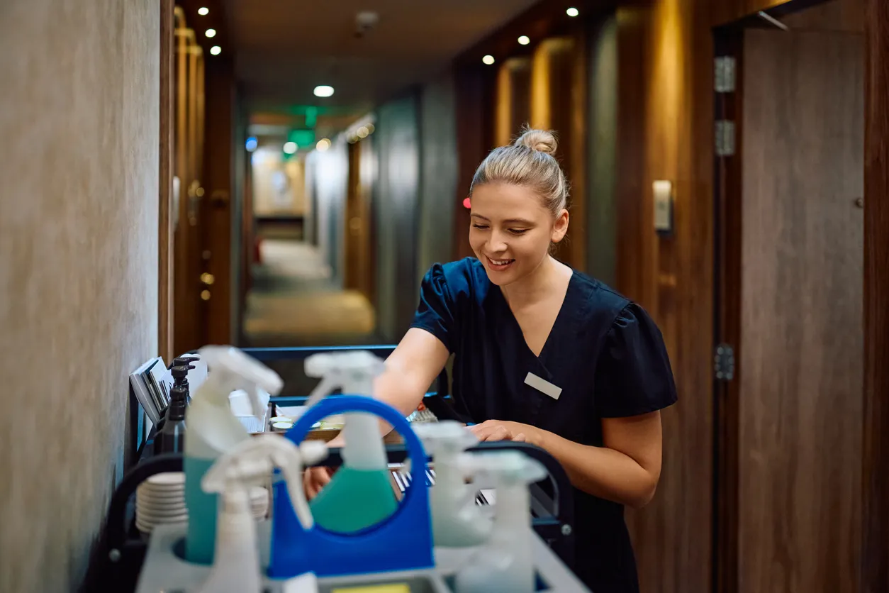Mujer joven feliz trabajando como camarera en un hotel, realizando la limpieza. 