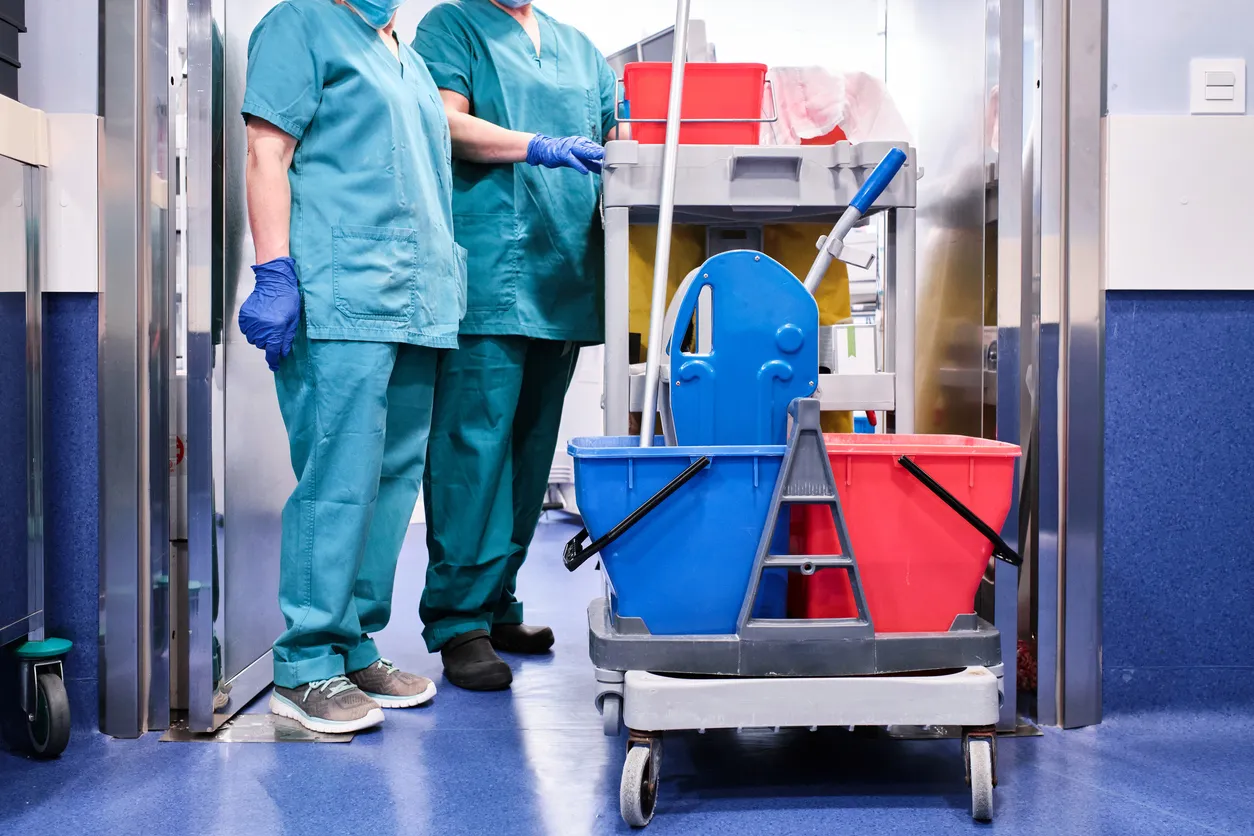 Personal de limpieza junto a un carrito de limpieza en un hospital.