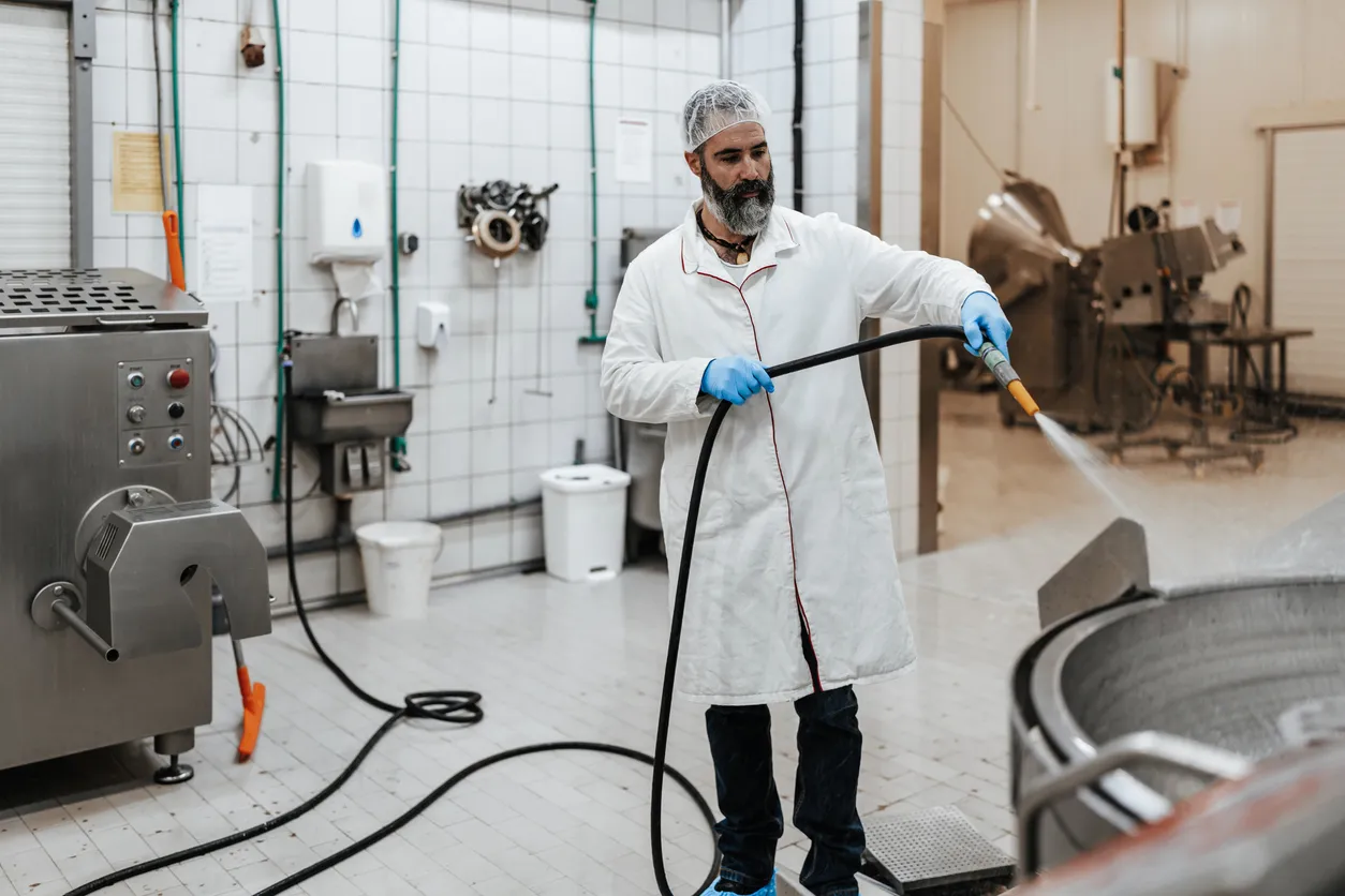 Hombre de mediana edad con experiencia limpiando y desinfectando la línea de producción de carne cruda.