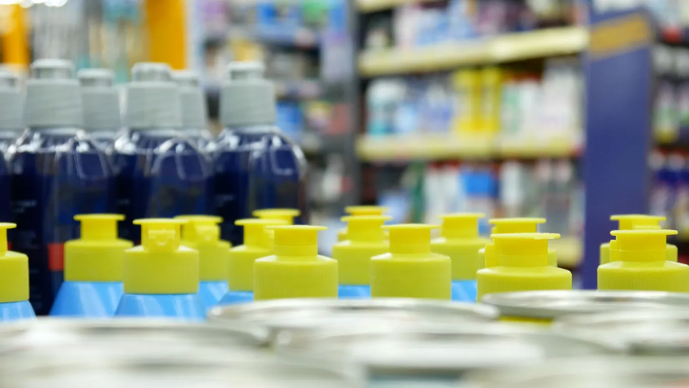 Primer plano de muchas botellas de líquidos lavavajillas y detergentes en el mostrador de una tienda