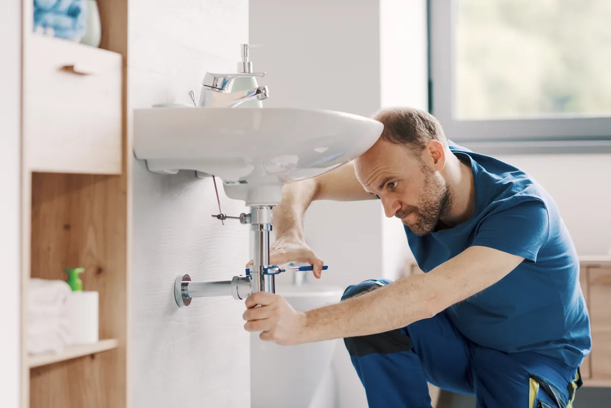 Fontanero profesional instalando un lavabo del baño a la altura adecuada