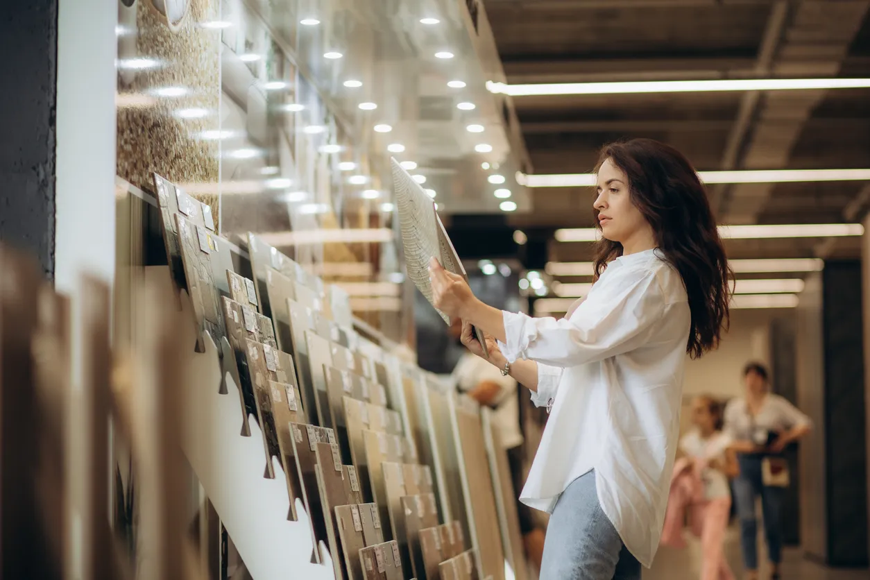 Mujer seleccionando piso en gran bodega de venta de azulejos.