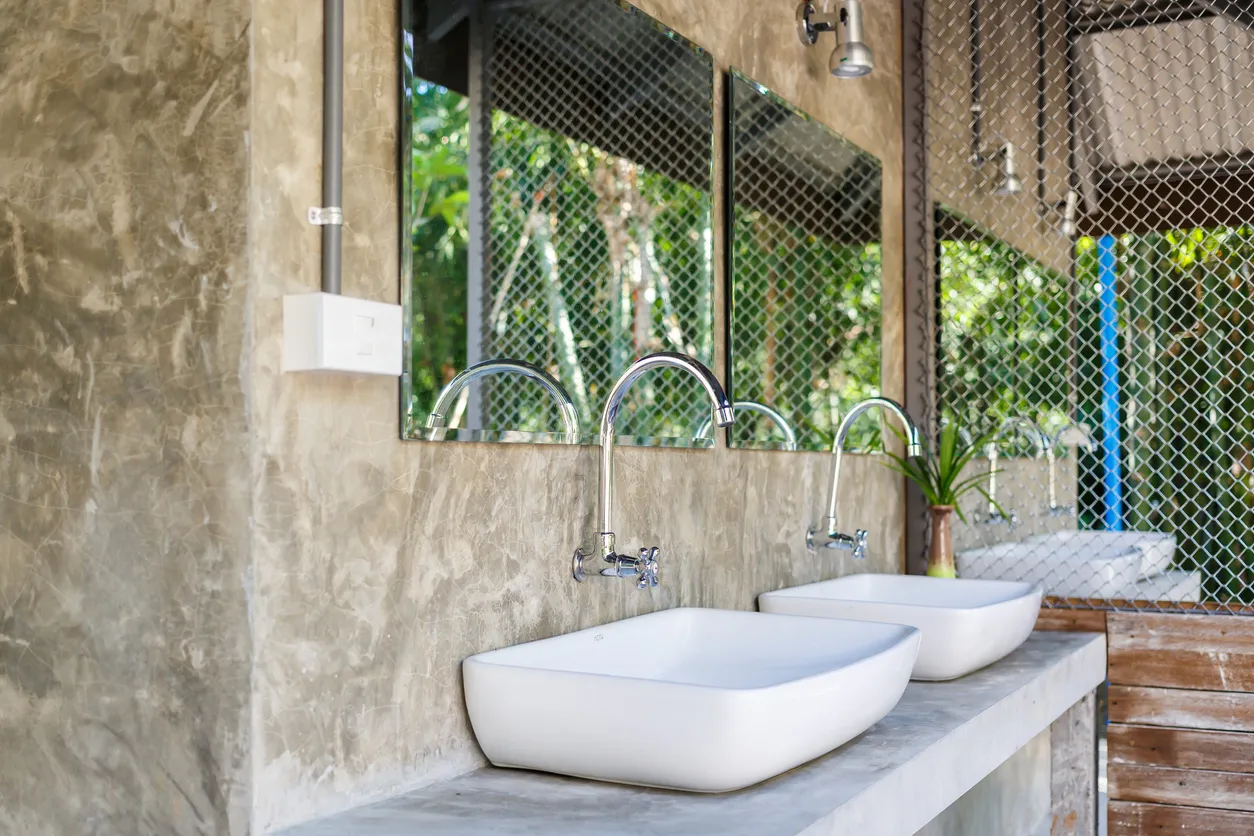 Varios lavabos en color blanco sobre base de cemento en el exterior