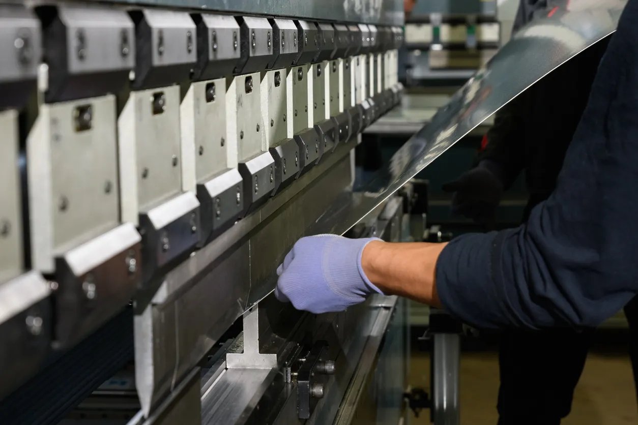 Trabajador operando una prensa de metal en el taller