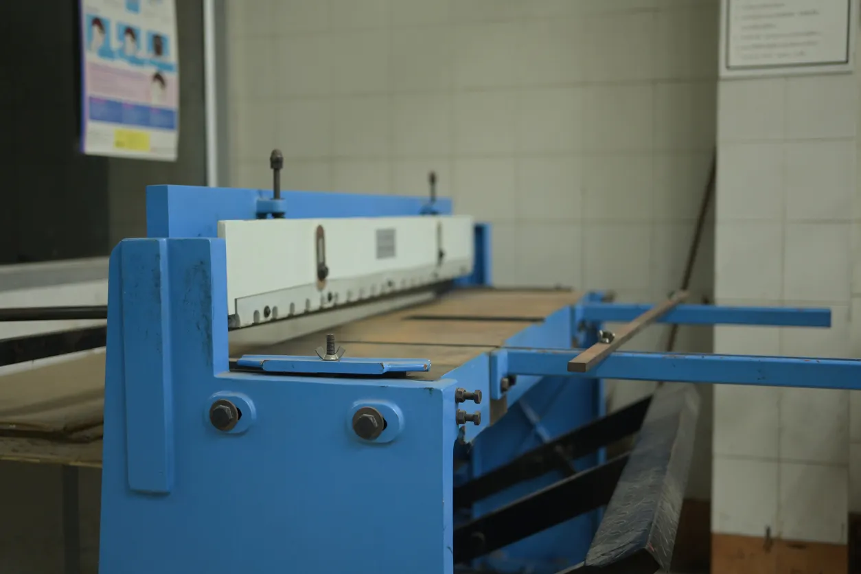 Una robusta cizalla de pie azul en un taller de impresión, diseñada para cortar con precisión papel y placas de metal.