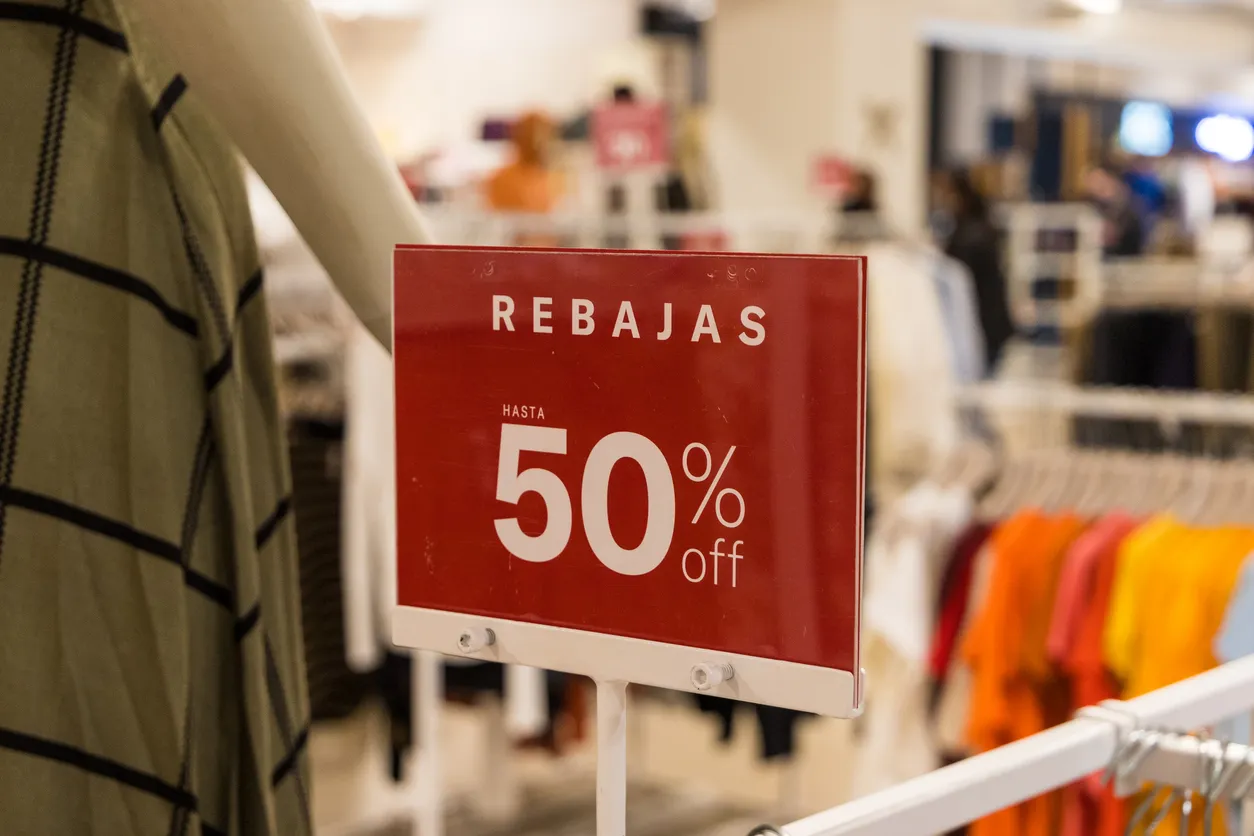 Se muestra letrero de rebaja del 50% en un exhibidor de una tienda de venta de ropa para dama