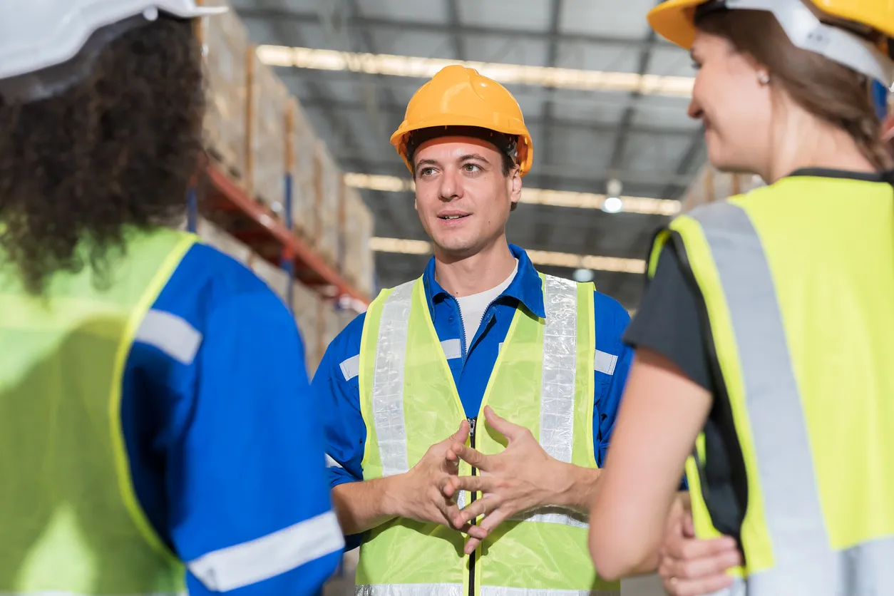Trabajadores de almacén con uniformes, chalecos y cascos de seguridad