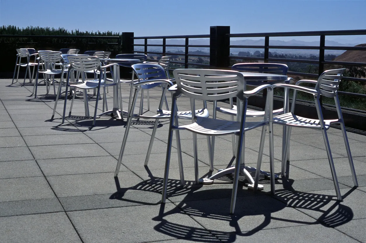 Terraza con varias sillas y mesas de aluminio. 