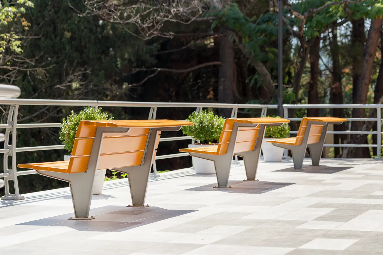 Modernos y cómodos bancos de madera, amplios y luminosos, en un parque urbano.