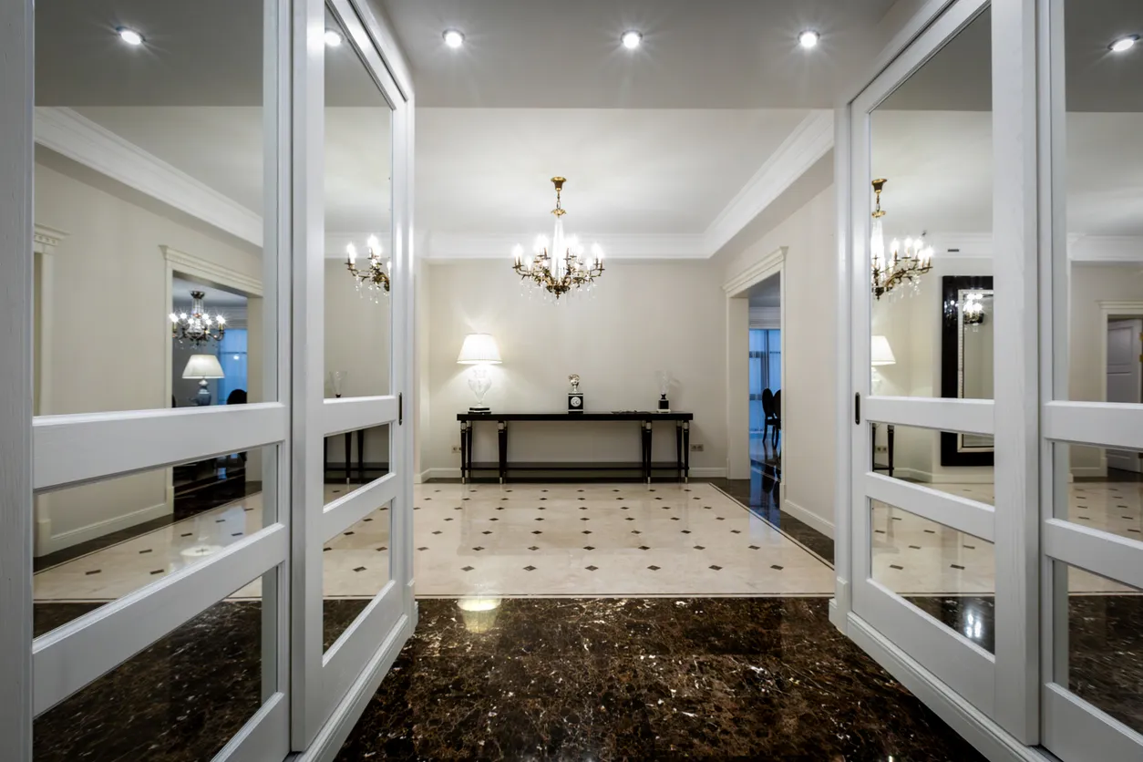 Pasillo con espejos de diversos tamaños a ambos lados y al fondo una habitación iluminada