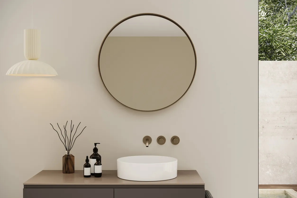 Gran espejo redondo con marco negro y pared color beige y mueble de madera con lavabo de encimera. 