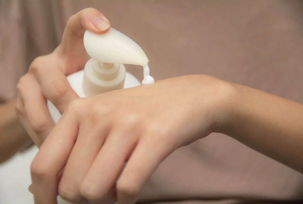 Mano de mujer aplicándose una crema repelente contra insectos en sus manos 