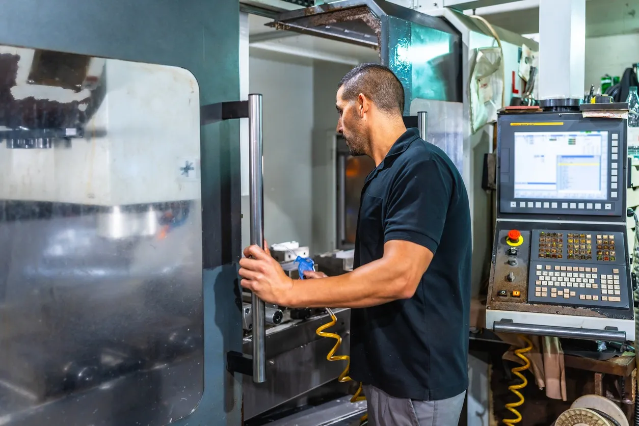 Técnico utilizando comandos de fresadora en una fábrica CNC
