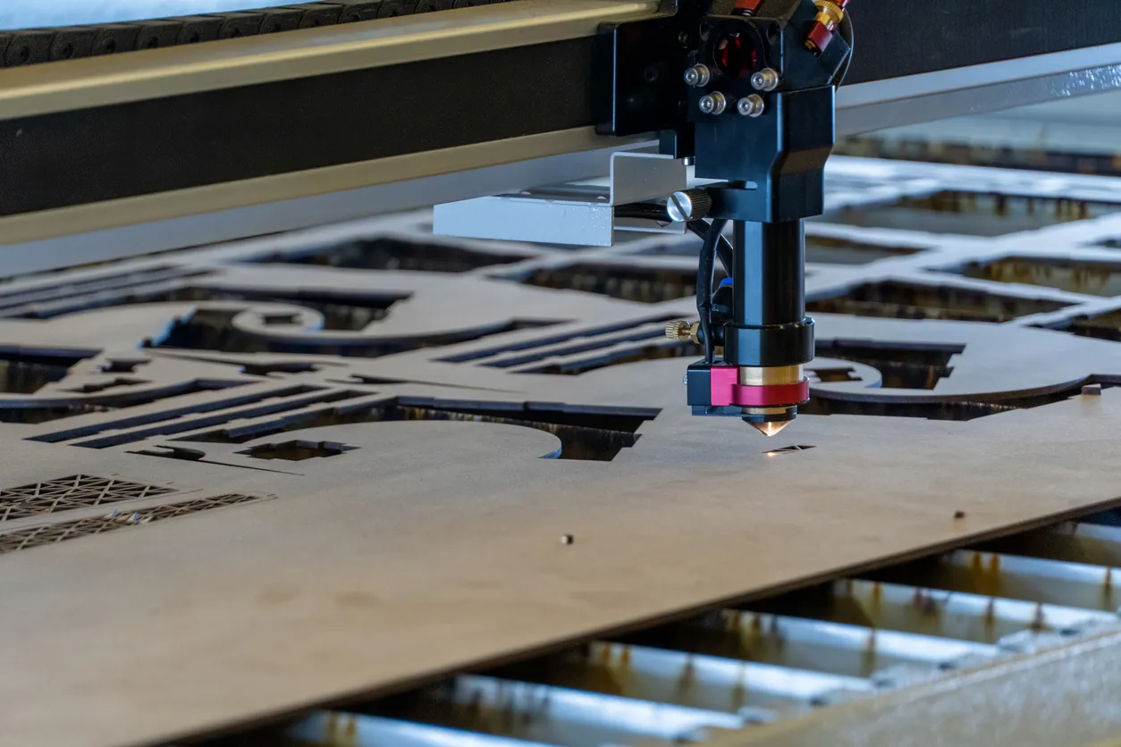 Laser cutting machine, cutting wood sheets, while a man records the process