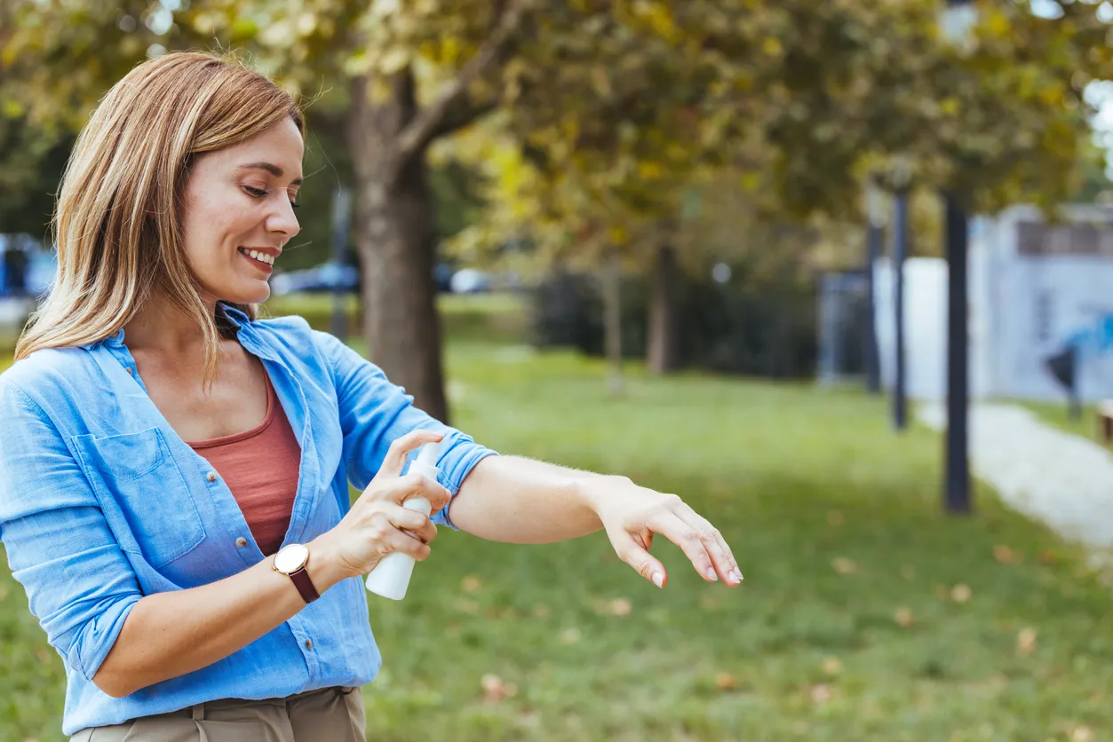 Mujer caucásica aplicándose repelente de mosquitos al aire libre
