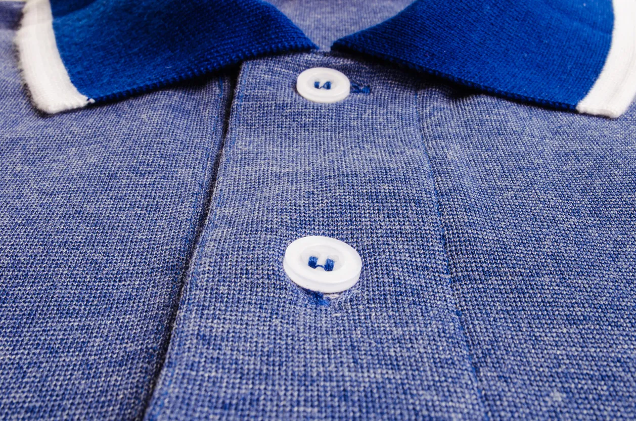Vista cercana de una playera polo de punto combinada de color azul y cuello azul y blanco 