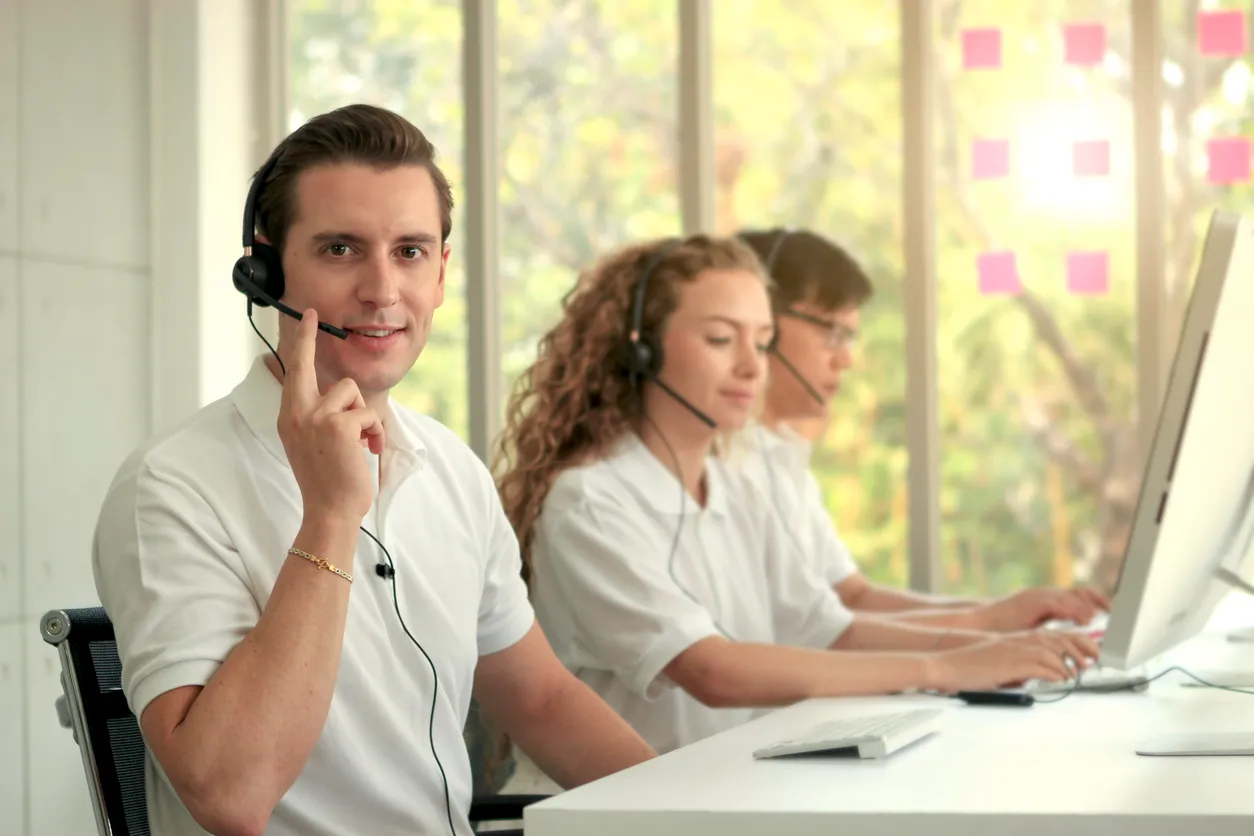 Varios jovenes en oficina de atención a clientes con playeras polo beige
