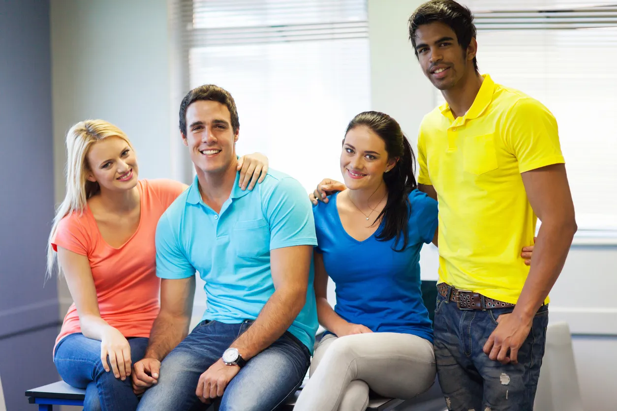 Cuatro jóvenes con playeras de diversos colores.