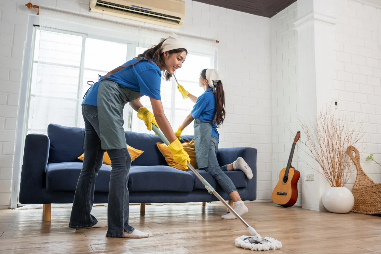 Equipo de limpieza de mujeres limpiando el interior de la sala de estar en casa.