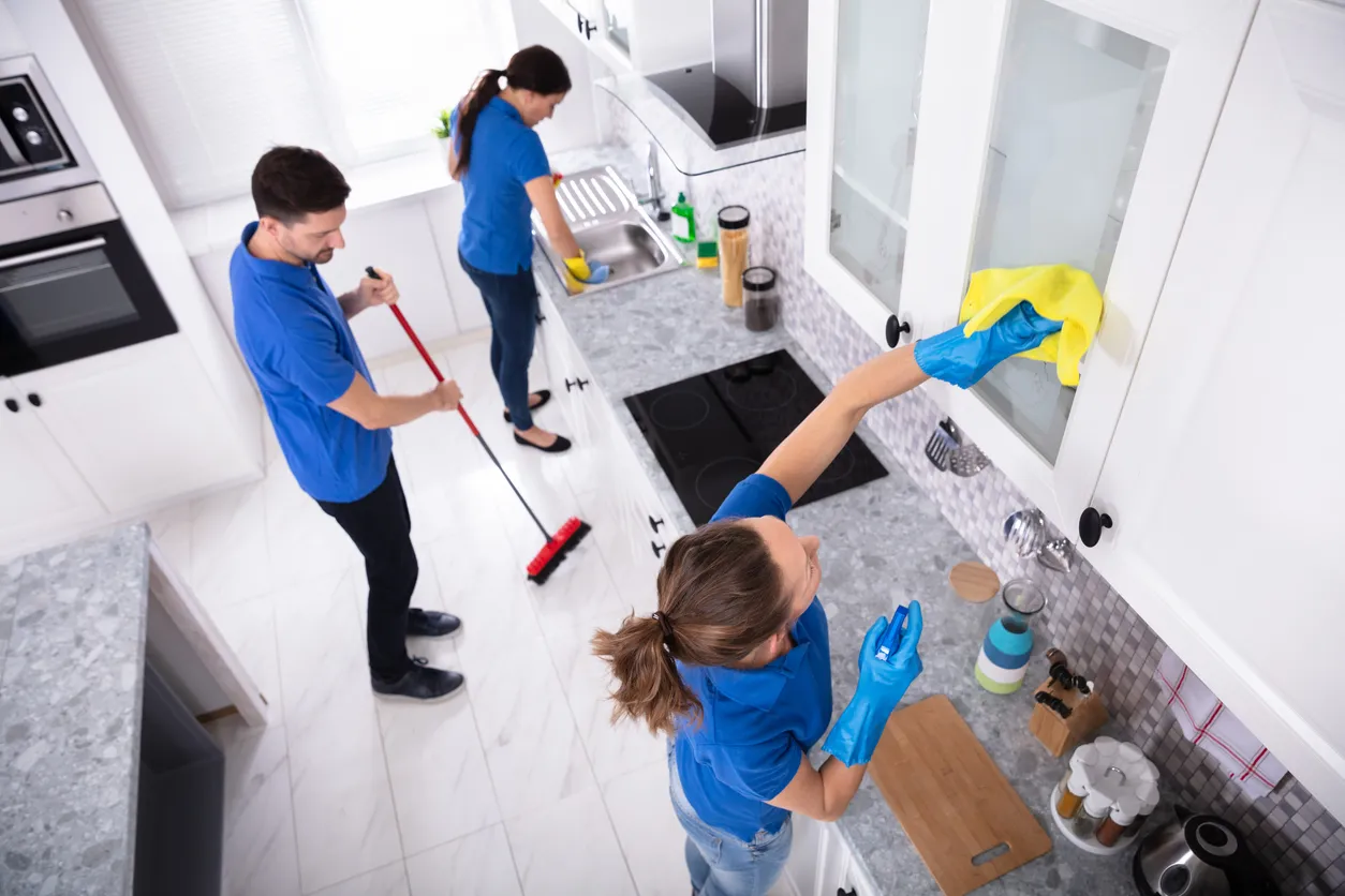 Tres personas realiando la limpieza de la cocina de una casa.