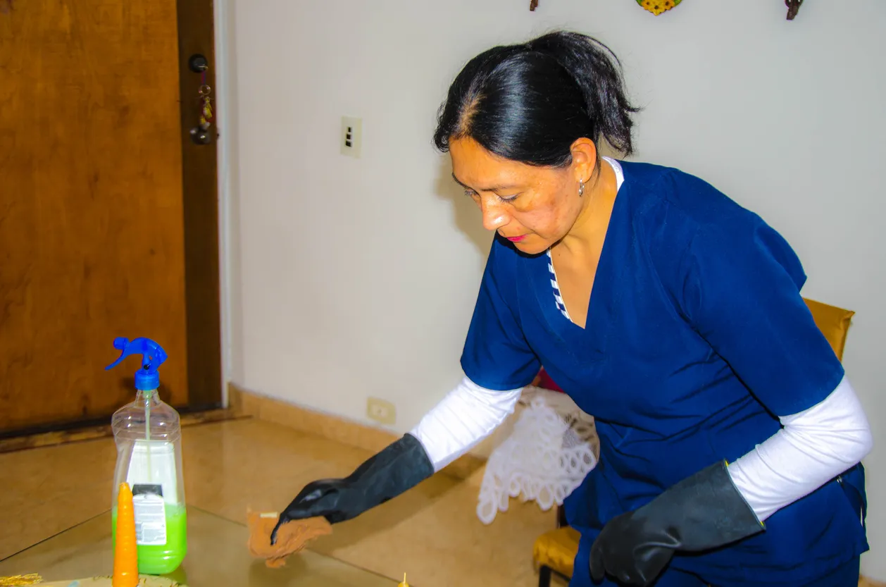 Señora de limpieza realizando la limpieza de una mesa