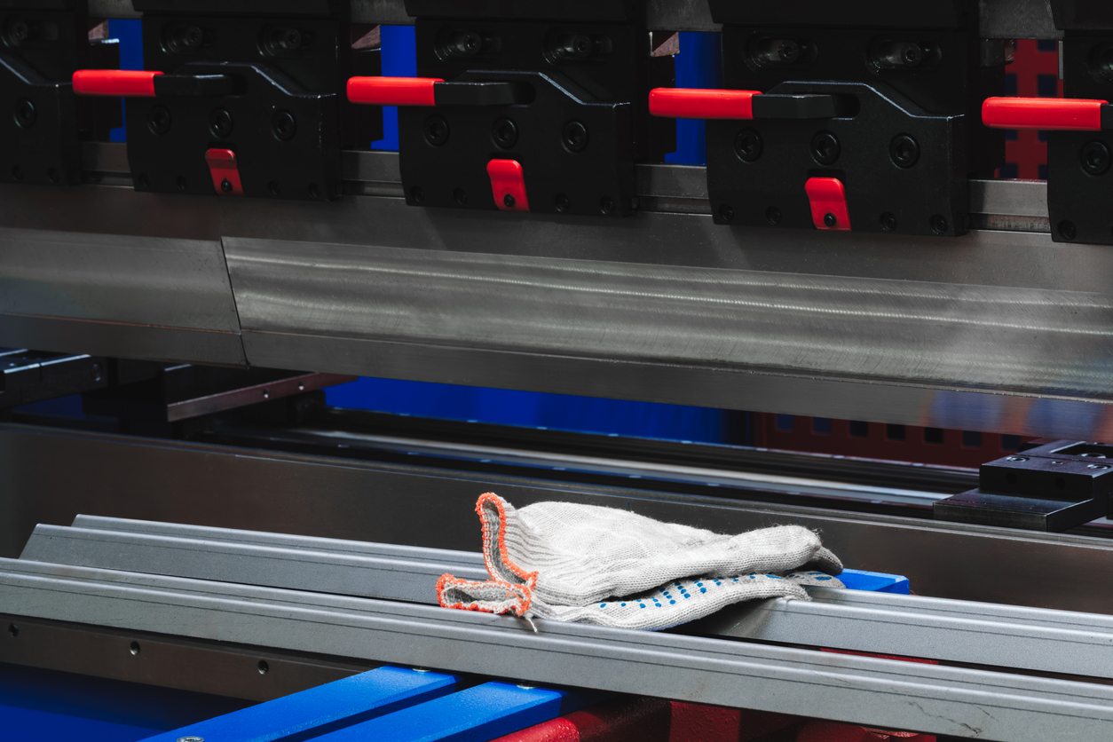 Guantes de trabajo usados por el operador en máquina de trabajo de metal dobladora, antecedentes del concepto industrial