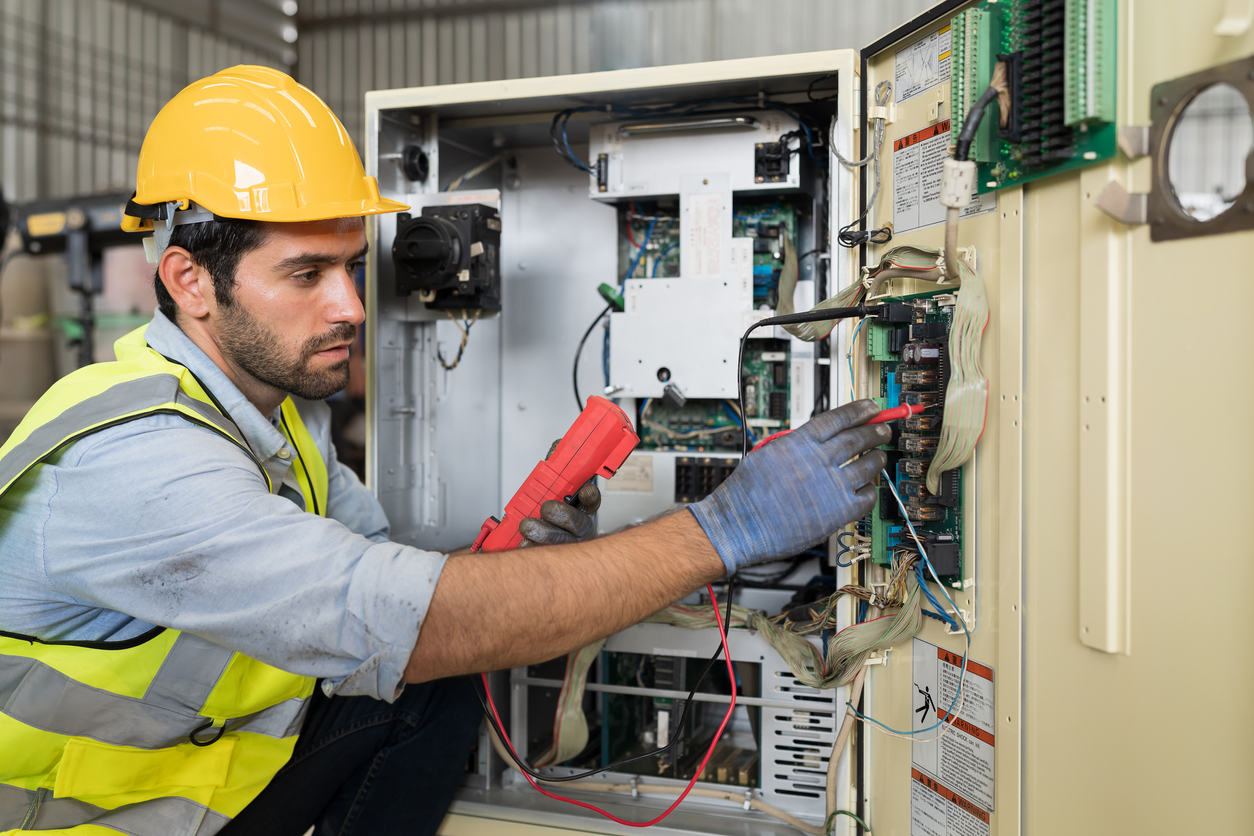 Trabajador electricista masculino verificando, reparando, operación de mantenimiento del sistema eléctrico en fábrica