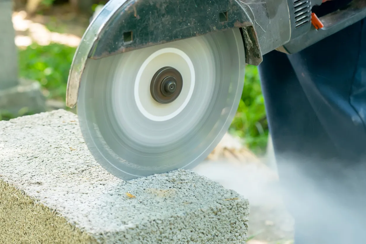 Trabajador cortando bloques de hormigón con amoladora angular.