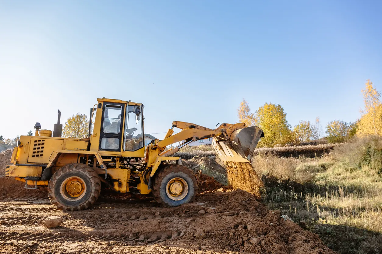 Una gran cargadora de ruedas amarilla nivela un terreno para una nueva construcción. Preparación del terreno