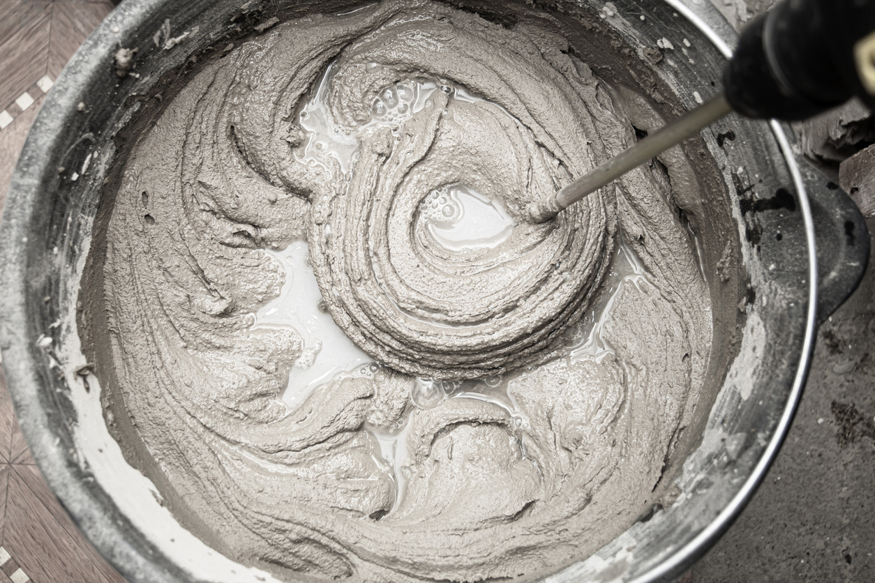 Adhesivo a base de cemento. Mezcla de hormigón con un taladro eléctrico y mezclador.