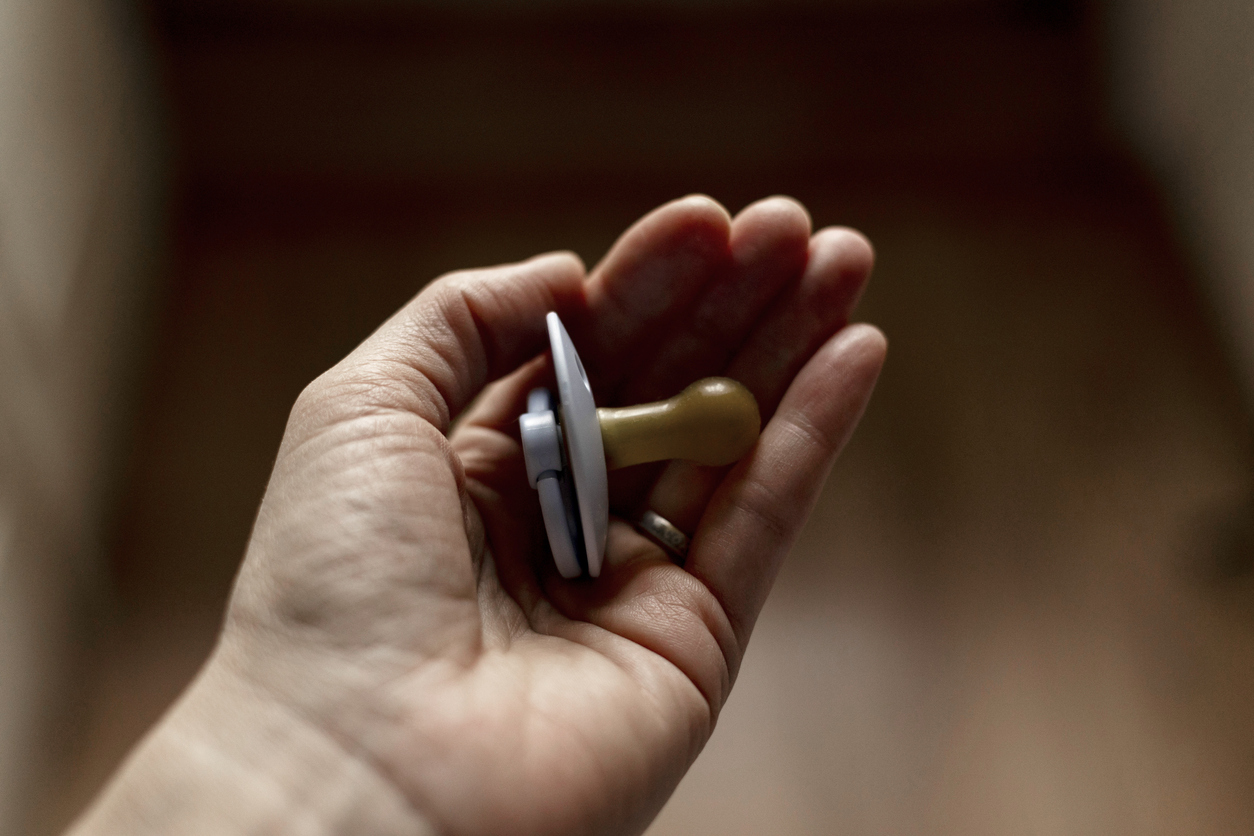 Primer plano de una mano acunando suavemente un chupete.