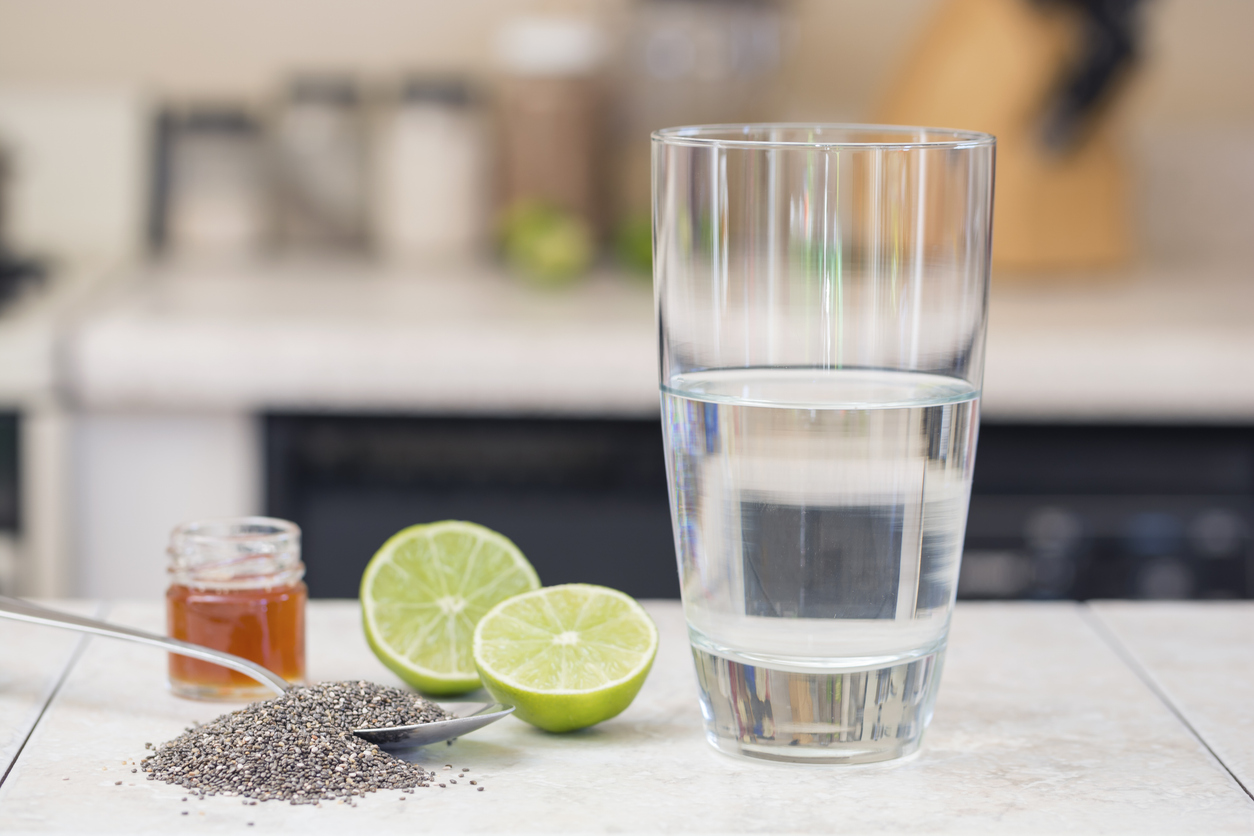 vasos con diferentes jugos cítricos sobre fondo negro, junto a trozos de limón maduro y lima con hojas