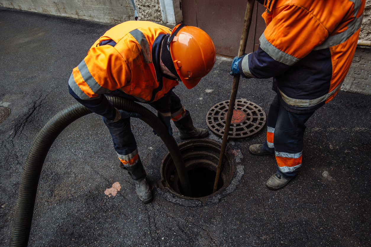 Trabajadores de alcantarillado limpiando alcantarillas y desatascando alcantarillas en la acera de la calle