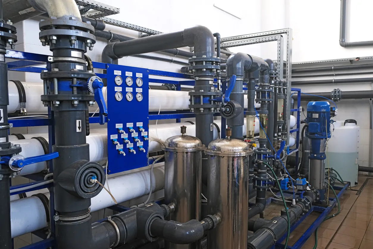 Sala interior de una planta de tratamiento de aguas residuales con tuberías y numerosos indicadores manómetros