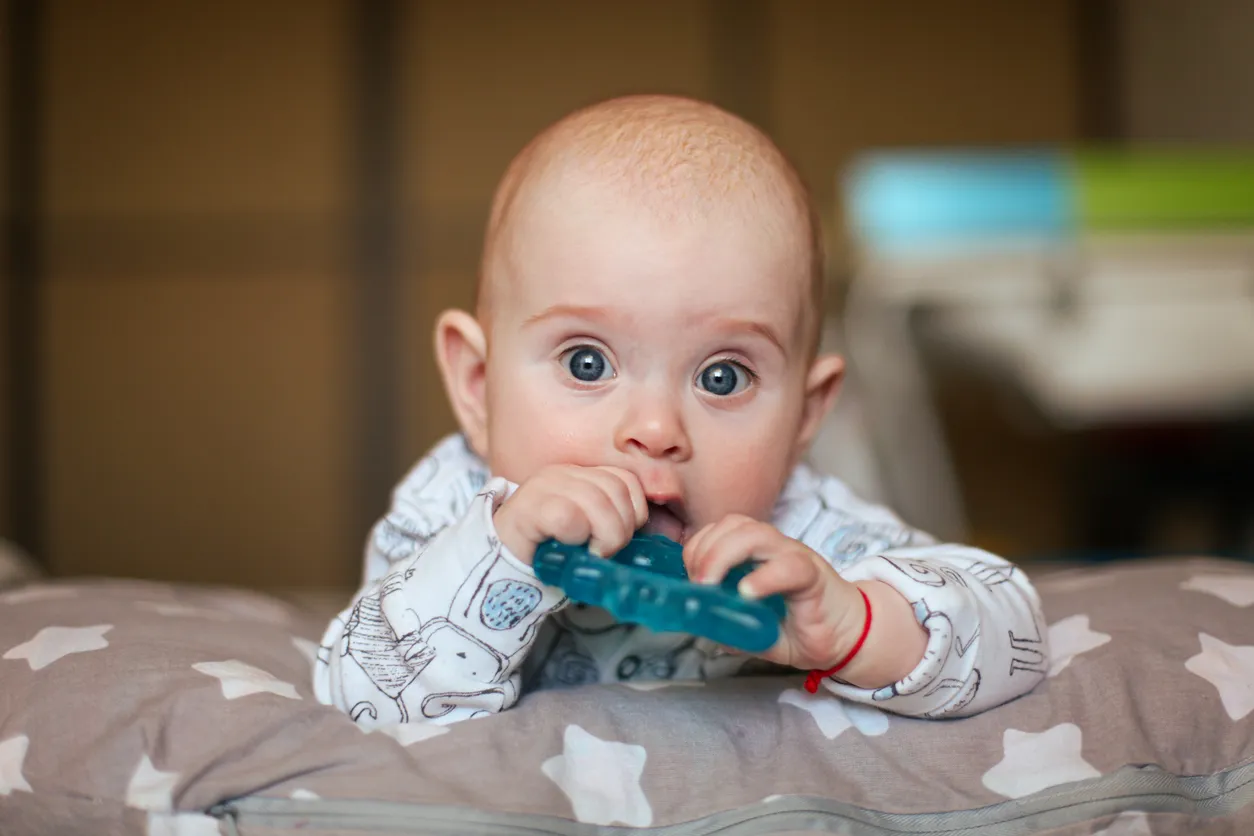 Bebe en cama con mordedera en la boca