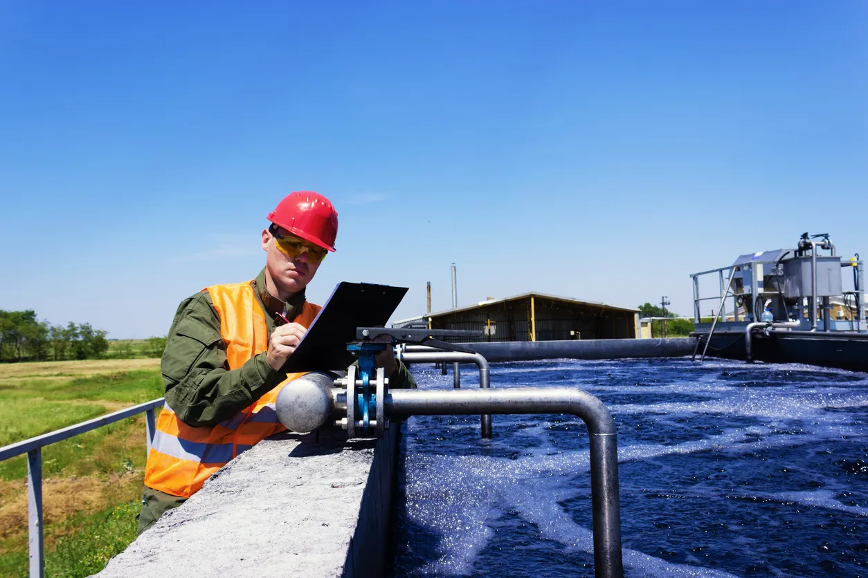 Trabajador inspeccionando una válvula para filtrar agua, en planta de tratamiento de aguas