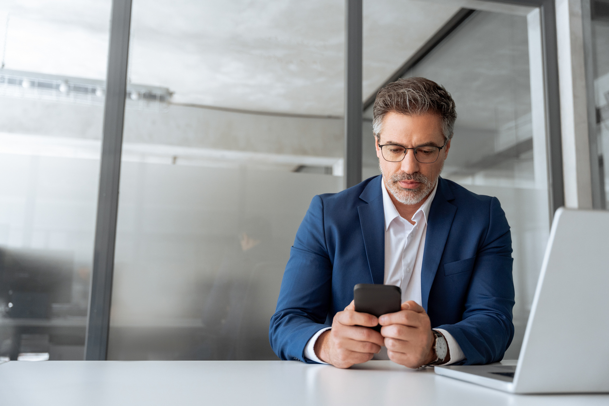 Hombre con amputación parcial de la mano sonriendo y mirando la pantalla del teléfono celular
